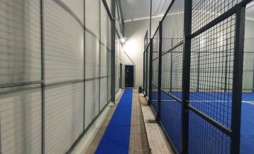 Widok ściany i ogrodzenia przy boisku do padla w hali