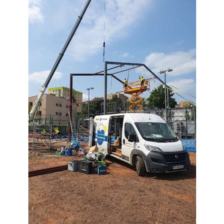 Stawianie konstrukcji hali do padla - prace z użyciem dźwigu i podnośnika
